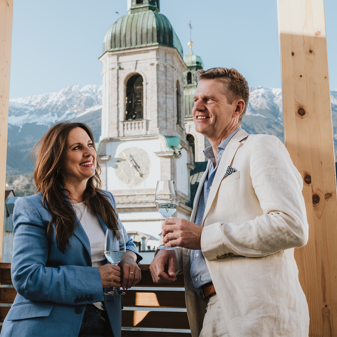 Paar genießt Wein vor atemberaubendem Dom und Bergen: Perfekter Moment im Innsbruck Hotel.