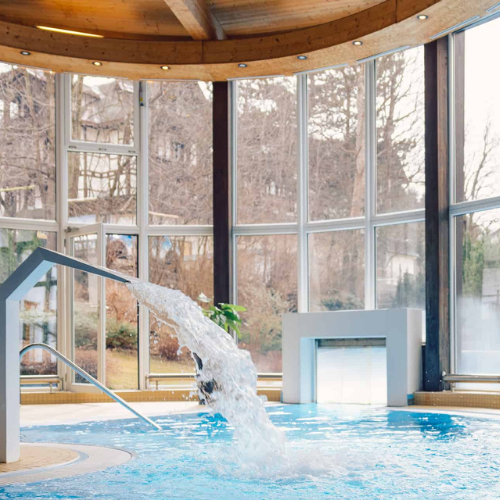 15 Innenpool im Innsbruck Hotel mit Wasserspiel und Panoramafenster, umgeben von Natur. Entspannen und genießen.