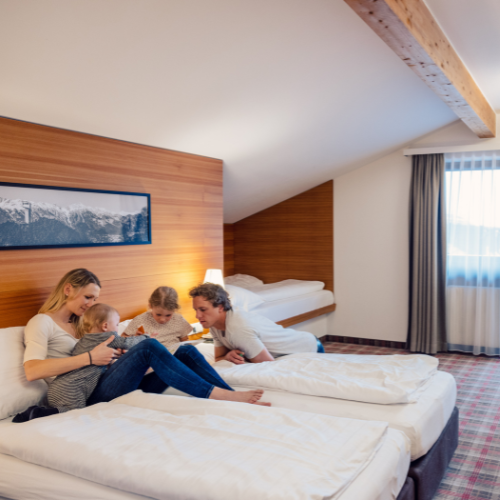 16 Familie genießt gemütliches Zimmer im Innsbruck Hotel mit Bergblick – ideal für einen erholsamen Urlaub.