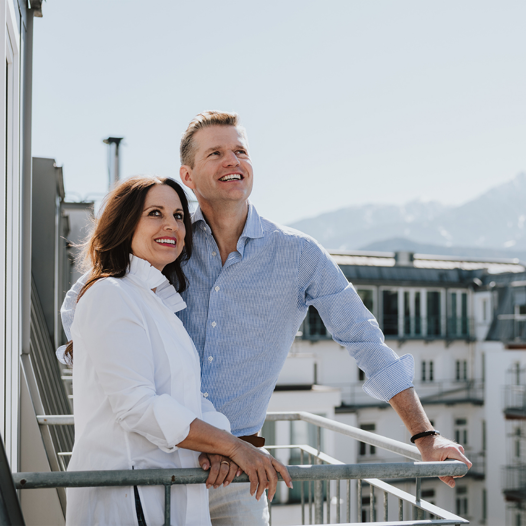 sffbgsh Paar genießt den Ausblick vom Balkon eines Innsbruck Hotels mit Alpenblick.